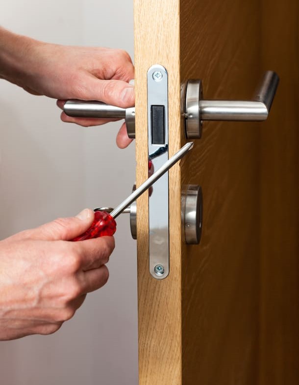 Hände reparieren ein Türschloss